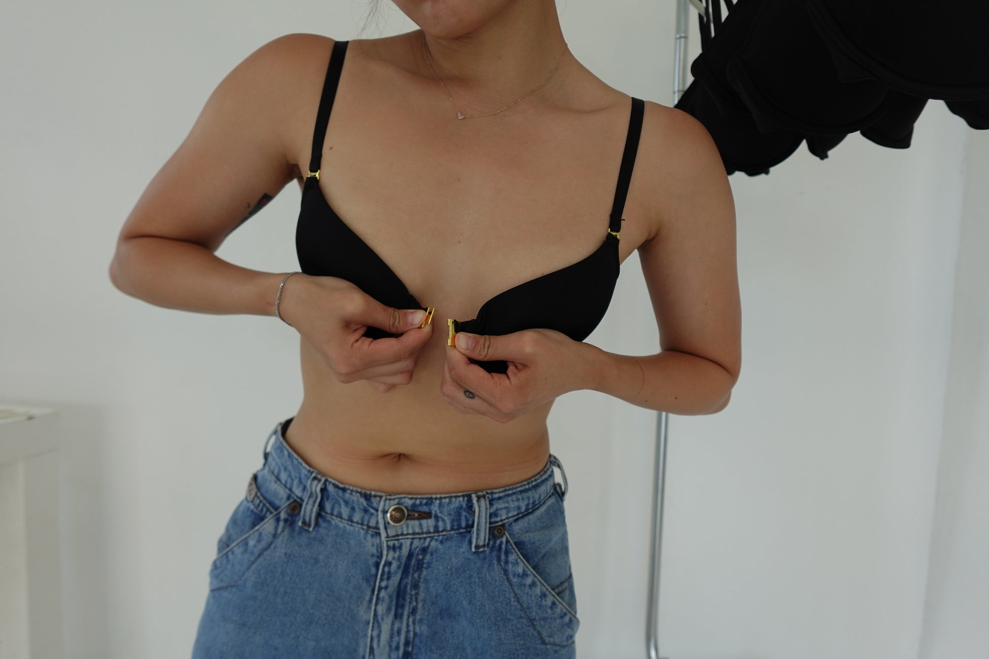 Model demonstrating the front clasp closure on a Sui Generation black modular bra, designed with independent left and right cups to fix uneven breasts.